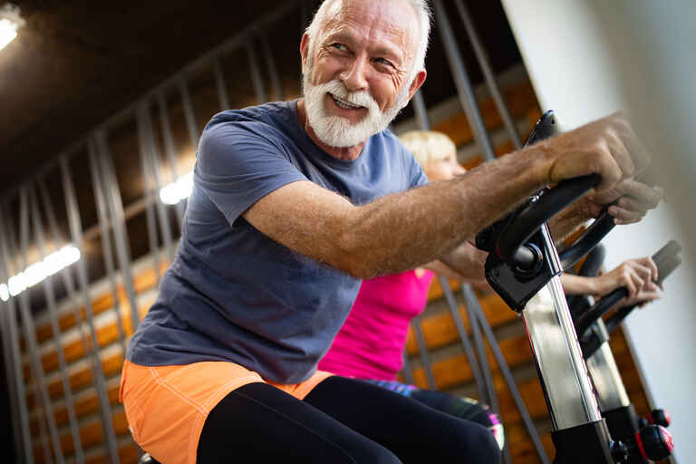 Happy mature people doing exercises in gym to stay fit